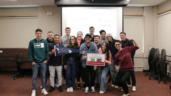 Students from OC and UNOESCO pose in a classroom.