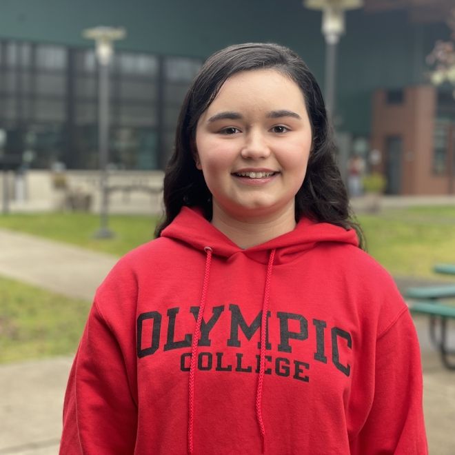 Smiling student in red Olympic College sweatshirt, outside of Shelton Campus Bldg. 1