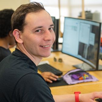 Student working at computer smiling at the camera