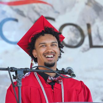 OC student in cap and gown at podium at graduation. 