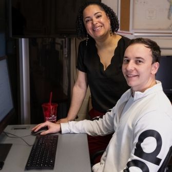 Military and veteran program staff assisting student at computer