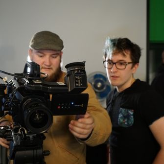 Two students on either side of a video camera