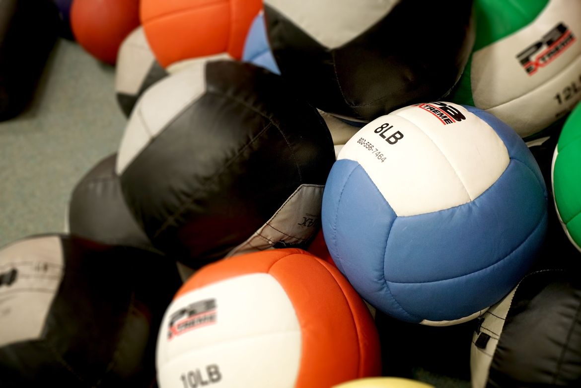 Pile of colorful stitched exercise balls on gym floor.