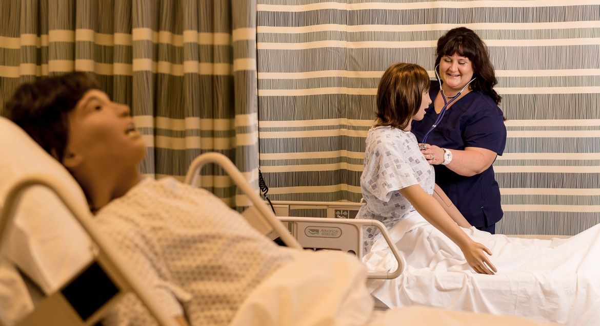 Nursing student with simulation mannequin.