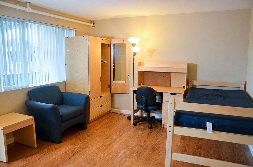 Interior of a room in the residence hall featuring a bed, closet, desk and chair