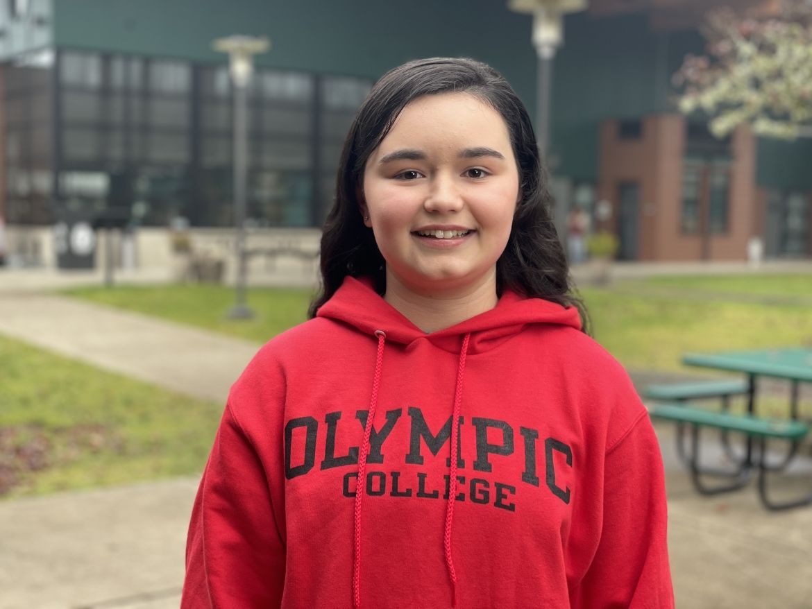 Smiling student in red Olympic College sweatshirt, outside of Shelton Campus Bldg. 1