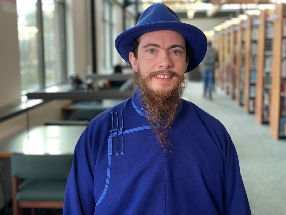 Smiling student poses near windows in Haselwood Library