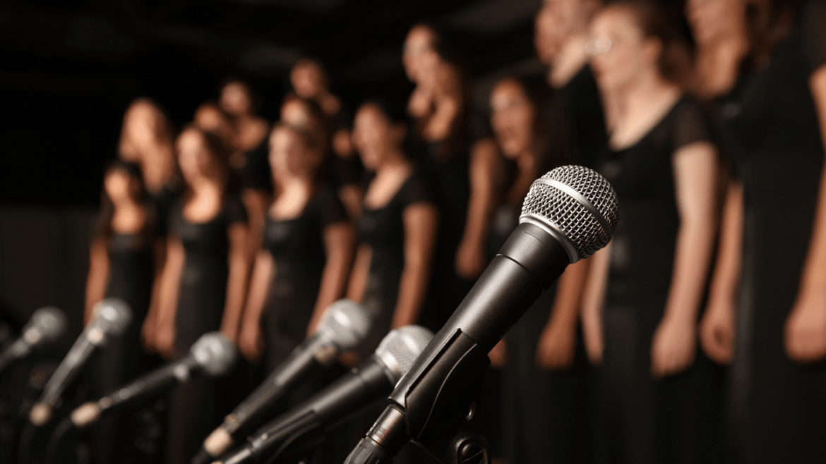 Concert choir dressed in black with microphones in the foreground. 