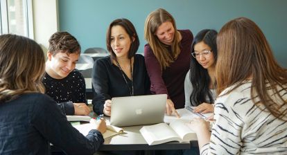 Instructors assisting students seated at a table