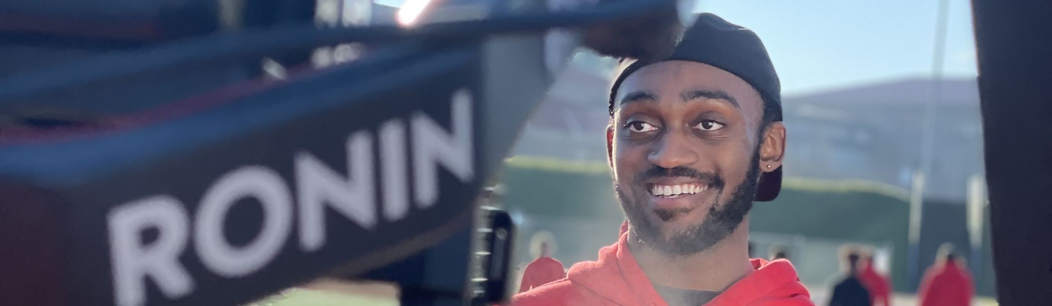 Student athlete standing on track and smiling for a camera.