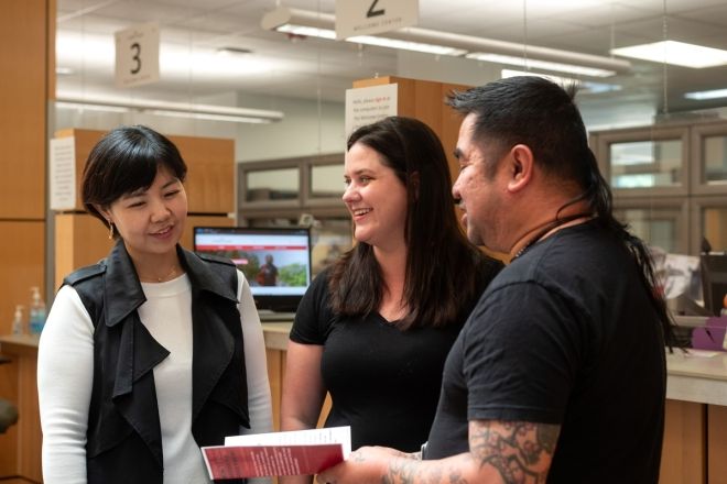 Photo of three people speaking with each other
