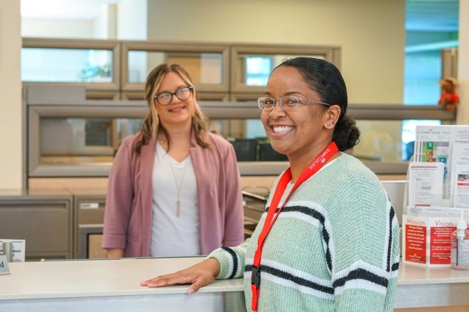 Two female students at enrollment counter. 