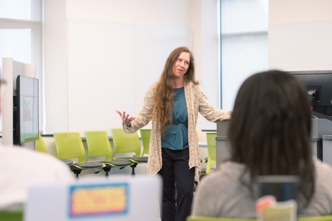 A female instructor teaching to a classroom filled with students