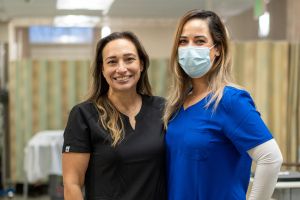 Two women in scrubs smiling