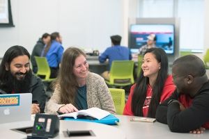 Teacher with students at desk with laptop. 