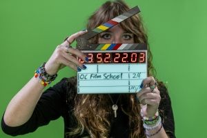 Film student operating clapperboard in front of green screen