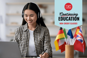 A woman sitting at a computer beside a cup filled with flags of various countries. Text reads, "Olympic College Continuing Education Non-Credit Classes"