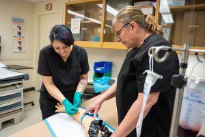 Two Phlebotomy students working in a lab