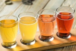 row of small glasses containing different color liquids on a wood tray