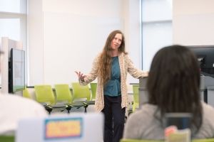 A female instructor teaching to a classroom filled with students