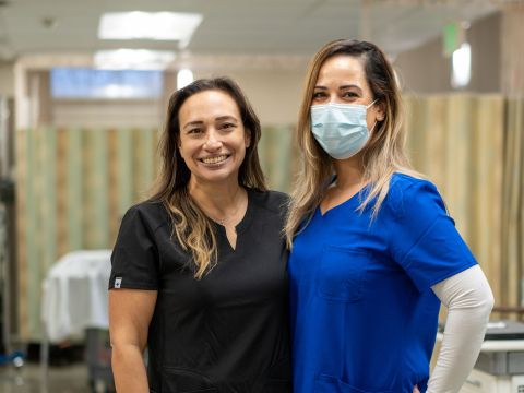 Two women in scrubs smiling