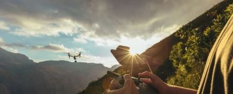 Landscape with a drone in the air and person controlling it remotely