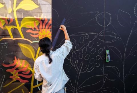 Photo of a woman painting a mural