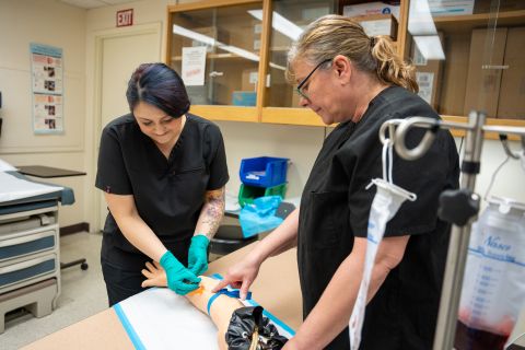 Two Phlebotomy students working in a lab