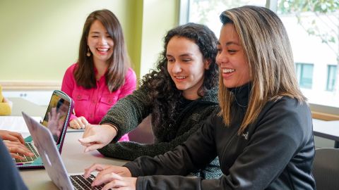 Three students at laptop in class.