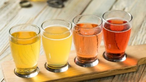 Food_beverage.png row of small glasses containing different color liquids on a wood tray