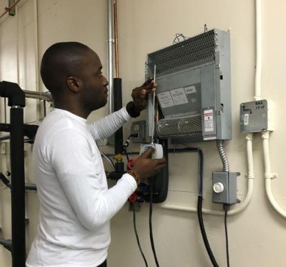 An electrical engineering student inspecting an electrical box