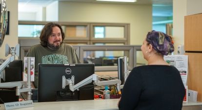 Male employee with student at counter.